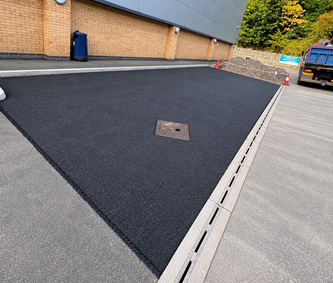 Newly surfaced parking and access area at St Clare's School in Sheffield, with new kerb line and channel drainage along the edge